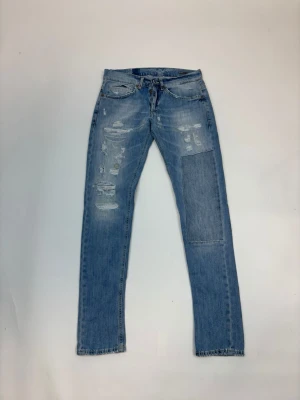 Dondup - Ljusblå jeans med slitningar och en stor patch på höger ben. Klassisk femficksmodell med raka ben och råa kanter vid benslut. Jeansen har en avslappnad vibe och är perfekta för en trendig streetstyle-look.