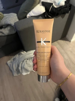 Kérastase Curl Manifesto hårkräm - Kérastase Curl Manifesto Crème de Jour Fondamentale är en närande leave-in-kräm för lockigt hår. Tuben är beige med silverfärgat lock och rymmer 150 ml. Produkten hjälper till att återfukta, definiera och skydda lockarna utan att tynga ner håret.