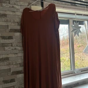 Brun långklänning från Ellos - Snygg brun långklänning från Ellos i mjuk bomull. Klänningen har v-ringad hals och korta ärmar med rynkade detaljer. Enkel och stilren design som ger en chill vibe. Perfekt för dig som gillar bekväma och trendiga plagg.