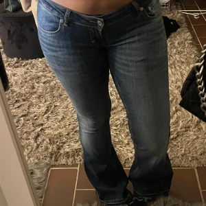 Blå bootcut jeans med låg midja - Snygga blå jeans med bootcut passform och låg midja. Jeansen har klassisk femficksdesign, lätt tvättad look och är tillverkade i jeansmaterial. Perfekta för dig som gillar en avslappnad men trendig stil. Storlek M, full length och uppsprättade (jag är 170)