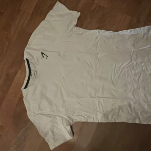 Vit T-shirt från Gymshark - En helt oanvänd tröja från gymshark. Den är lite som en compression tröja eftersom den är liten i storleken. Vill gärna bli av med tröjan och darför de låga priset.