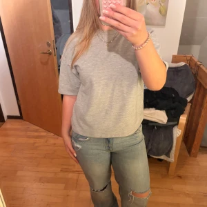 Grå t-shirt från ZARA - En basic grå t-shirt från ZARA i storlek S. T-shirten har en rak och lite loose passform med korta ärmar och rund halsringning. Perfekt att styla med jeans eller shorts för en enkel och clean look. Sweatshirt material
