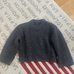 Mörkgrå stickad tröja Gina Tricot - Mysig mörkgrå stickad tröja från Gina Tricot med grov ribbad struktur och rund halsringning. Tröjan har lång ärm och en lite boxig, loose passform som ger en chill vibe. Perfekt att slänga på sig när det är kallt ute.