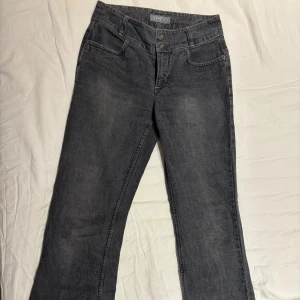 Grå jeansbyxor från Esprit - Snygga grå jeansbyxor från Esprit med utsvängda  ben och klassisk femficksdesign. Byxorna har dubbla knappar i midjan och kontrastsömmar. Perfekta för dig som gillar en enkel och stilren look. Materialet är mjukt och bekvämt jeans.