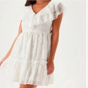 Vit volangklänning med v-ringning - Superfin vit kortklänning med volanger och v-ringning. Perfekt för sommaren, aldrig använd prislappen är kvar 