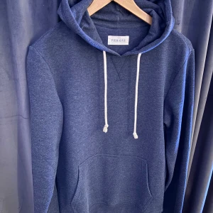 Hoodie från Pier One - Mysig mörkblå hoodie från Pier One med klassisk känguruficka och vita snören i huvan. Tröjan har lång ärm och är tillverkad i mjukt material, perfekt för chill dagar. Enkel och stilren design som funkar året runt.