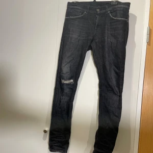 Dondup - Svarta jeans från Dondup i skinny fit-modell, storlek 32. Jeansen har klassisk femficksdesign, slitning vid ena knät och smal passform hela vägen ner. Materialet är jeans med lite stretch för extra komfort. Perfekt för dig som gillar en tajt siluett. Knappt använd 