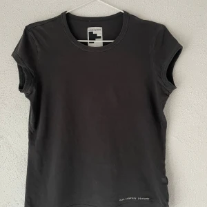 Svart t-shirt från J.Lindeberg Denim - Svart t-shirt från J.Lindeberg Denim i storlek L. Modellen är klassisk med rund hals och korta ärmar. Materialet är mjuk bomull och har en diskret text '21st century pioneer' nedtill. Perfekt för en clean och enkel look. Skulle säga att det är storlek s