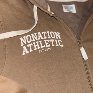 Nonation Athletic zip up - Ljus brun zip up storlek M men passar också storlek S. Den är i bra skick 9/10 Inga hål eller trasiga sömmar. Använd fåtal gånger. Säljer då den inte passar längre
