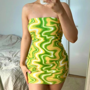 Tubklänning från NA-KD i grönt och gult 💛 - Supersnygg kort bandeau klänning från NA-KD, storlek XS. Stretchigt material och har ett tjockt resårband upptill så den ej ska åka ner. Fint skick 💛