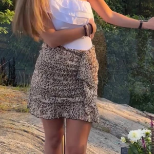 Leopardmönstrad volangkjol - Säljer en kort kjol med leopardmönster och volangdetaljer. Färgerna går i beige och brunt, och materialet är lätt och luftigt.