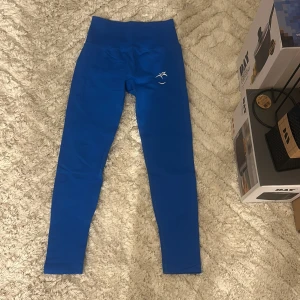 Blå höga leggings från Peach - Snygga blå leggings från Peach med hög midja och ribbade detaljer vid bensluten. Stretchigt material som sitter tight och formar kroppen. Perfekta för träning eller chill. Diskret logga framtill och tydlig Peach-tryck baktill.