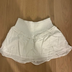 Vit volangkjol från Gina Tricot - Säljer en vit volangkjol ifrån Gina som är i linne, har en brun fläck på sig men annars inga konstigheter, skriv om ni har några funderingar💕
