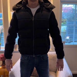 Mörkblå pufferjacka Polo Ralph Lauren - SKRIV FÖR KVITTO eller fler bilder. Säljer en mörkblå pufferjacka från Polo Ralph Lauren med huva och tvåvägsdragkedja. Säljer den samt för att den är lite liten. Jackan har quiltad design, elastiska muddar och snygga detaljer i blankt material upptill. Perfekt för kalla dagar och riktigt stilren look.