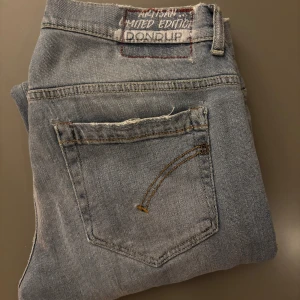 Ljusblå jeans från Dondup - Snygga ljusblå jeans från Dondup med klassisk femficksdesign och slitna detaljer på fickor och ben. Jeansen har raka ben och normal passform, med en cool limited edition-label baktill. Perfekt för dig som gillar en avslappnad streetstil. *limited edition modell med skräddar gjorda slitningar*. Storlek 31 midja: 42cm längd: 101cm. Fint skick, inte så använda.