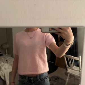 Ljusrosa stickad topp - Säljer en supermjuk ljusrosa stickad topp med korta ärmar och rund hals. Toppen är croppad och har en enkel, clean look som är lätt att matcha med jeans eller kjol. Perfekt för dig som gillar rosa och vill ha en cozy vibe.