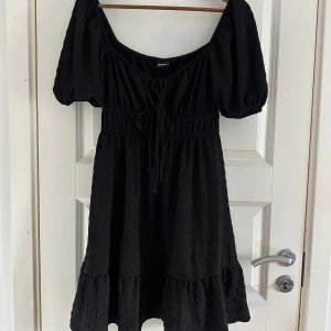 Svart kort klänning från Gina Tricot - Supersöt svart klänning från Gina Tricot med puffiga korta ärmar och knytning framtill. 