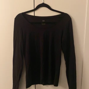 Svart långärmad tröja KappAhl XS - En svart långärmad tröja från KappAhl, Our Best Basics, i ekologisk bomull. Tröjan har en enkel och stilren design med rundad hals och smal passform. Perfekt som basplagg och lätt att matcha med andra kläder.