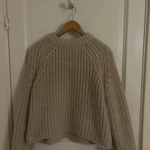 Beige stickad tröja från H&M - Säljer en chunky stickad tröja från H&M i beige färg. Tröjan har grov ribbstickning, rund hals och långa ärmar. Perfekt för att hålla sig varm under kyliga dagar. Passformen är loose och den är riktigt mysig att bära.