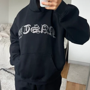 Svart hoodie med glittrig text 🖤 - Svart Hidden Cult huvtröja. Storlek M i fint skick. På framsidan finns en stor strassdekor med texten 'NASTY' i gotisk stil. Tröjan har en loose passform och är tillverkad i mjukt bomullsmaterial, perfekt för chill dagar. Har även tillhörande mjukisbyxor i en annan annons 🖤