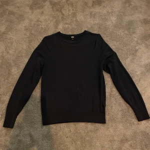 Svart stickad tröja från Uniqlo - En stilren svart stickad tröja från Uniqlo i merino ull. 