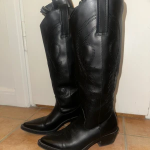 Svarta boots  - Snygga svarta boots med klassisk broderad dekor och spetsig tå. Låg klack och högt skaft. 