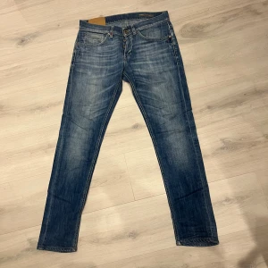 Dondup - Snygga Dondup jeans i klassisk blå tvätt med lätt slitningar. Modellen har fem fickor, knappgylf och subtila detaljer på bakfickorna. Perfekt passform. Jeansmaterialet är mjukt och följsamt.