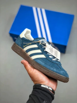 Adidas Spezial blå sneakers - Adidas Spezial sneakers i blå mocka med vita detaljer och klassiska tre ränder på sidan. Skorna har brun platt gummisula, rund tå och snörning. Märket 'Spezial' i guld på sidan och vit häl. Perfekt för dig som gillar retrostil och streetwear.