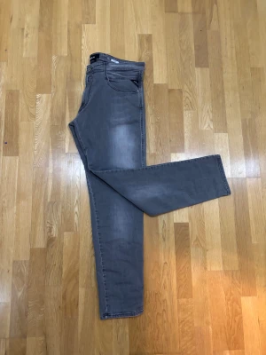 Replay Anbass grå jeans 36/32 - Snygga Replay Anbass jeans i grå tvätt med klassisk femficksdesign och raka ben. Byxorna har diskreta slitningar och ton-i-ton sömmar, samt Replay-logga på bakfickan. Materialet är mjukt jeans med lite stretch för extra komfort. Kan också passa 34/30. Och är i otroligt bra skick, pris kan DISKUTERAS