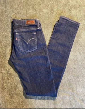 Levi's skinny jeans storlek 26X34 - Snygga mörkblå Levi's jeans i modellen Slight Curve med klassisk femficksdesign och tydliga kontrastsömmar. Skinny fit med smal passform hela vägen ner och normal midja. Materialet är slitstarkt jeans i bomull med lite stretch för extra komfort.