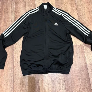Adidas jacka - Säljer Adidas jacka – som ny! 🧥 Fräsch och snygg Adidas originaljacka, nästan aldrig använd. ✅ Storlek: L (13-14 år) men passar Small storlek ✅ Färg: svart ✅ I mycket bra skick – inga fläckar eller skador. Perfekt för både vardag och träning! Skicka ett meddelande om du är intresserad! 👟✨Skickas snabbt 📦