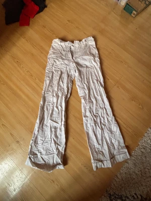 Vita linnebyxor med wide fit - Säljer ett par vita linnebyxor med breda ben och klassisk passform. Byxorna har dragkedja och knapp framtill, samt mjukt och luftigt linnematerial som är perfekt för varmare dagar. Stilen är loose och wide, vilket ger en chill och avslappnad vibe.