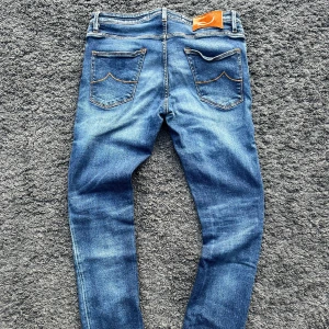 Jacob Cohën J696 COMF (Nick) - Jacob Cohën J696 Comfort i blå tvätt med snygg fade. Handgjorda i Italien med lyxig känsla, ikoniska detaljer.  📏 Mått: Innerben 77 cm, midja 42 cm, ytterben 104 cm 📐 Passform: Slim fit – strl 33, passar även 32 (98% bomull / 2% elastan) ✅ Skick: 9,5/10 - toppskick. Lite strån har fallit av uppe åt vänster på läderpatchen men inget som man varken tänker på eller känner vid användning. Denimet och allt annat är helt i toppskick utan defekter! 🧵 Modell: J696 Comfort 🧩 Material: Premium Denim fr 🇯🇵