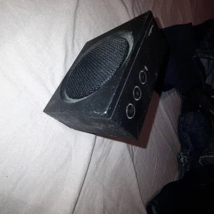 Nedis SPBT2000BK Bluetooth-högtalare + laddare - Kompakt Nedis SPBT2000BK Bluetooth-högtalare med tydliga knappar för volym och uppspelning. Svart färg, USB-laddning. Synligt yttre slitage och damm, men inga större skador. Perfekt för trådlös musik hemma eller på resan. Där finns en och en annan skråma men funkar perfekt som när jag köpte den! 