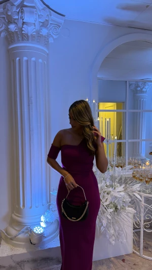 Lila långklänning med oneshoulder - Säljer en elegant lila långklänning med oneshoulder och figurnära passform. Klänningen har en snygg asymmetrisk axel och ärmlös design på ena sidan, medan den andra har en kort ärm. Materialet är mjukt och stretchigt, perfekt för att framhäva siluetten. Enbart använd en gång 