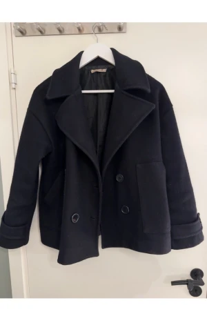 En mörkblå kavaj - En mörkblå kavaj med bred krage och dubbelknäppning. Jackan har stora fickor framtill och är perfekt för kyliga dagar. ☺️☺️☺️