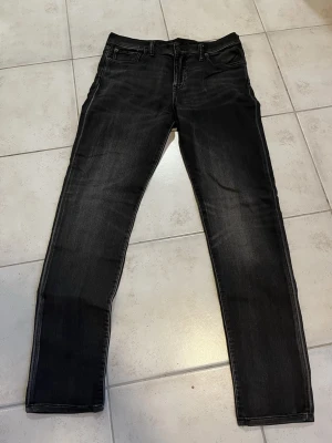 Svarta jeans från Polo Ralph Lauren - Säljer ett par svarta jeans från Polo Ralph Lauren med diskret tvättad look. Klassisk femficksmodell med raka ben och snygga sömdetaljer på bakfickorna. Jeansen har normal passform och är tillverkade i mjukt bomullsmaterial med lite stretch för extra komfort.