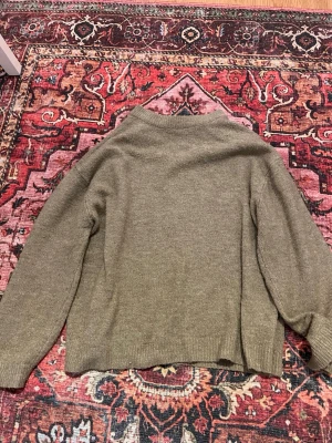 Beige stickad tröja med rund hals - Säljer en enkel och snygg beige stickad tröja med rundad hals och långa ärmar. Perfekt att slänga på sig när det är lite kyligt ute. Tröjan har en loose passform och ribbade muddar vid ärmslut och nederkant.