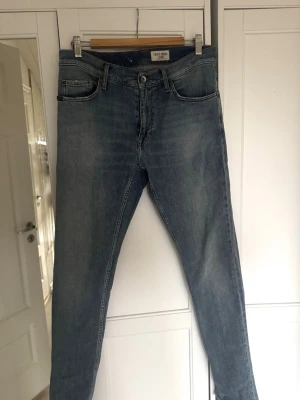 Blå jeans  - Säljer ett par klassiska blå jeans från Tiger of Sweden, med snyggt tvättad finish. Jeansen har normal midja och raka ben, jeansen är något ljusare i verkligheten! STORLEK: W31, L34