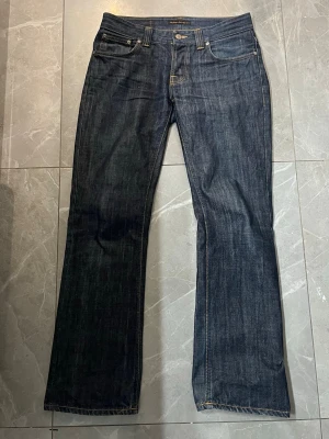 Nudie Jeans Bootcut Ola Dry - Säljer dessa feta och ovanliga Nudie Bootcut Ola!!! Dom är i väldigt bra skick, de är i storleken 31/32 men sitter mindre. Sitter straight med bootcut längst ner. Skriv vid minsta fråga/fundering🙌🏼  Midja: 38 cm Längd: 101 cm Benöppning: 22 cm