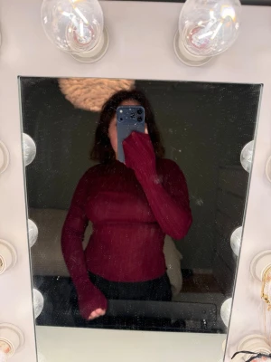 Vinröd långärmad polotröja - Säljer en vinröd långärmad polotröja i tunn, stretchig kvalitet. Tröjan har en tight passform och är perfekt att styla med jeans eller kjol. Enkel och stilren design utan synliga detaljer.