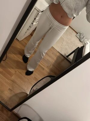 Vita bootcut mjukisbyxor med snörning - Säljer ett par vita mjukisbyxor med bootcut passform och snörning i midjan. Byxorna har en mjuk och stretchig känsla. De är midwaist och har en enkel, clean look. Dom är från lager 157, men lappen är bortklippt för att man ska kunna vika ner dom.