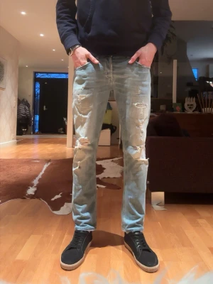 Dondup George 33 - Ljusblåa jeans med fabriksslitningar. Jeansen har lapp inutt i där det står 34 i stl men mått 43 cm så snarare 32/33. 