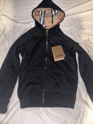Burberry Zip Hoodie Svart - Säljer nu min svarta Burberry hoodie då jag råkade köpa fel storlek. Pris kan diskuteras. Om ni har frågor är det bara att höra av sig🤗