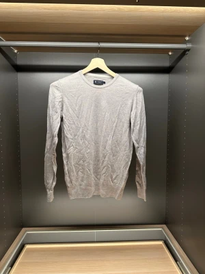 Beige merinoulltröja från Riley - Säljer en stilren beige tröja från Riley i mjuk merinoull. Klassisk rund halsringning och långärmad modell som passar perfekt till lager på lager. Enkel och clean design utan mönster eller detaljer, perfekt till jeans eller chinos. Den är storleken M men sitter som Xs/S för den har blivit tvättad fel