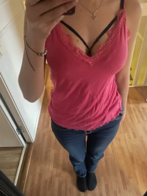 Rosa ribbad linnetopp med spets - Säljer en rosa ribbad linnetopp med smala axelband och v-ringning. Toppen har fina spetsdetaljer längs ringningen och är tillverkad i mjuk bomullsmix. Är XL men sister som en S