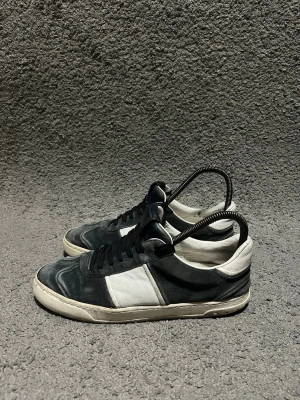 Valentino Flycrews - Säljer ett par snygga Valentino Garavani sneakers i svart och vitt. Skorna har svart mocka och vitt skinn, svarta skosnören och en vit sula med coola detaljer under. Klassisk låg modell med rund tå och diskret logga på plösen.