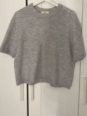 Stickad T-shirt - Grå stickad T-shirt från Gina tricot, den är nästan aldrig använd men har en rosa tråd i som jag såg efter jag köpt den, jag har inte försökt ta bort den men det går säkert. 