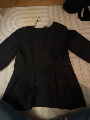 Svart peplum topp från Zara - Säljer en svart peplum topp från Zara med trekvartsärm och rund hals. Toppen har en markerad midja och utställd nederdel som ger en snygg siluett. Dragkedja där bak. Storlek S.❤️