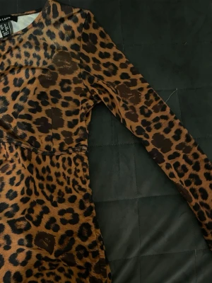 Leopardmönstrad topp från New Look - Säljer en leopardmönstrad långärmad topp från New Look. Toppen har rund halsringning, snörningsdetaljer i sidorna och är i ett stretchigt, mjukt material. Färgen är brun med svarta leopardfläckar och toppen har en figurnära passform. Angående frågor är det bara att höra av sig, gäller även diskutioner kring priset.